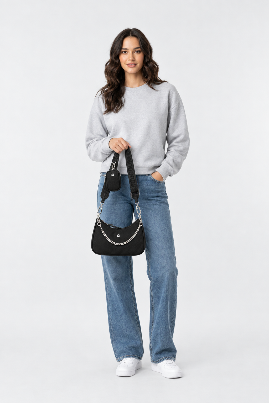 «Model houdt de Steve Madden Bdiego-H zwarte damestas met zilveren ketting vast in de hand, foto op volledige lengte»