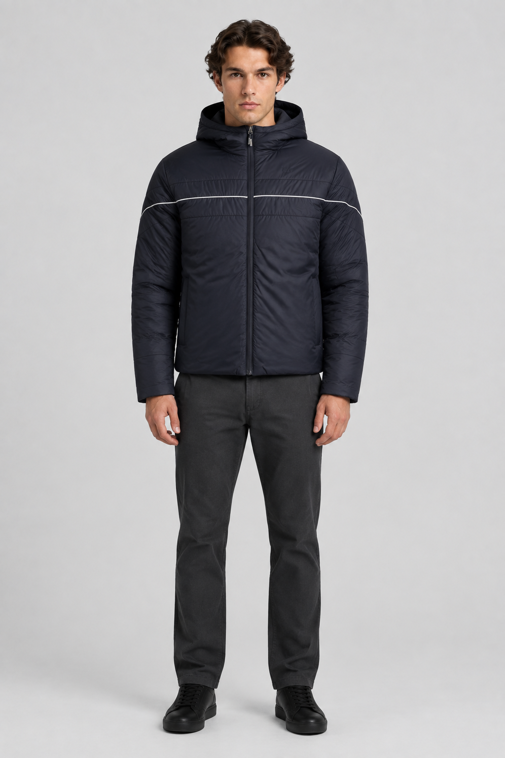 Mannelijk model met de donkere Ellesse Puffer Jas Pollas met capuchon en witte bies, volledig van voren gefotografeerd