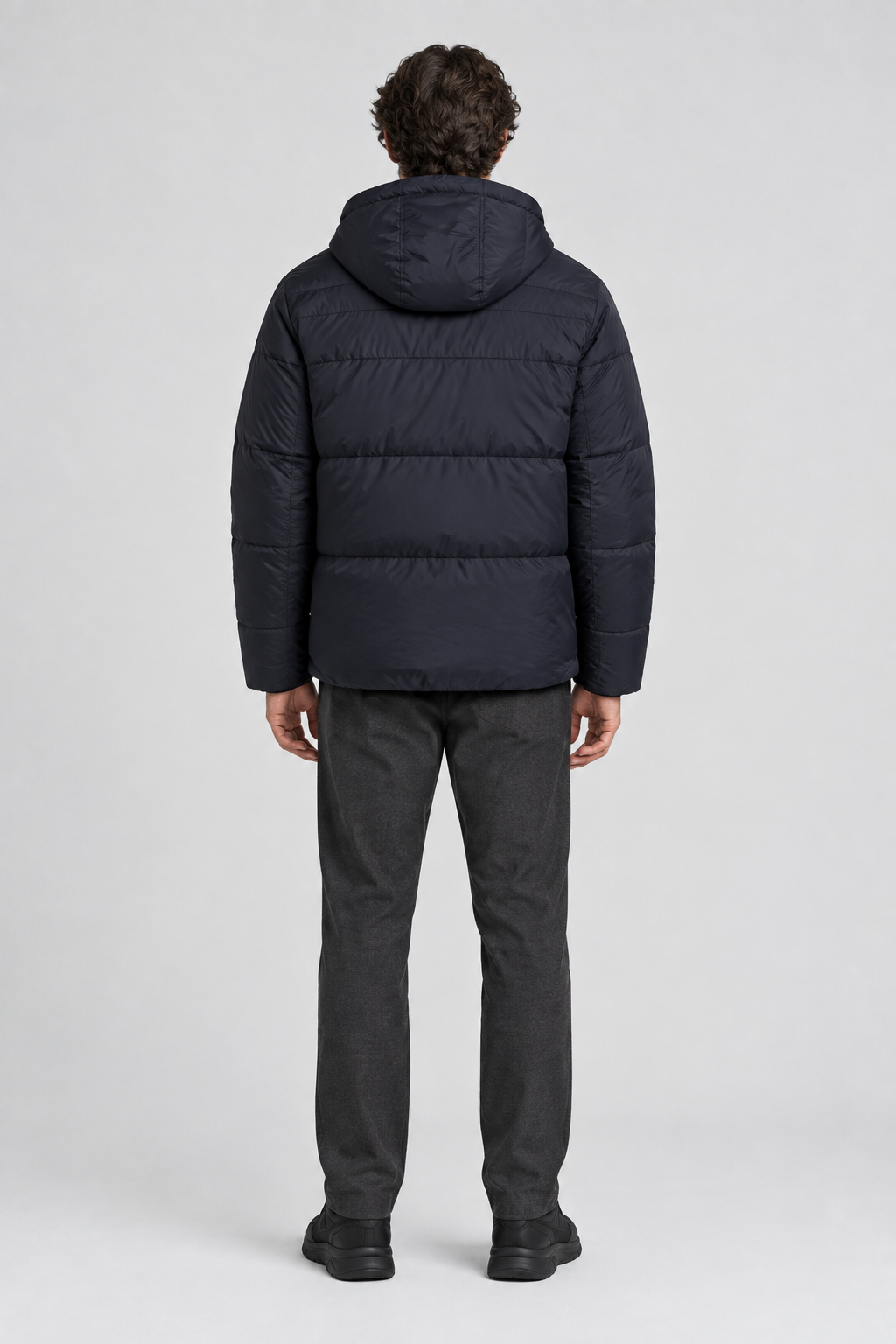 Mannelijk model met de donkere Ellesse Puffer Jas Pollas met capuchon, volledig van achteren gefotografeerd