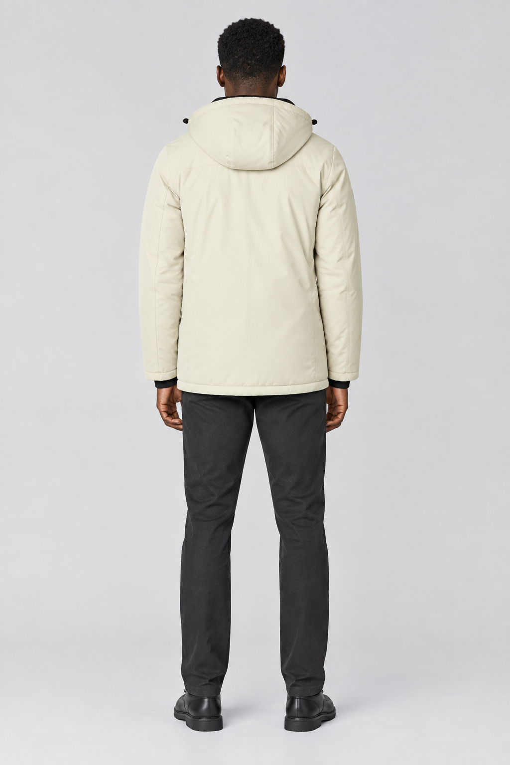 Mannelijk model met de lichtbeige Indicode Jas Viks met capuchon, volledig van achteren gefotografeerd