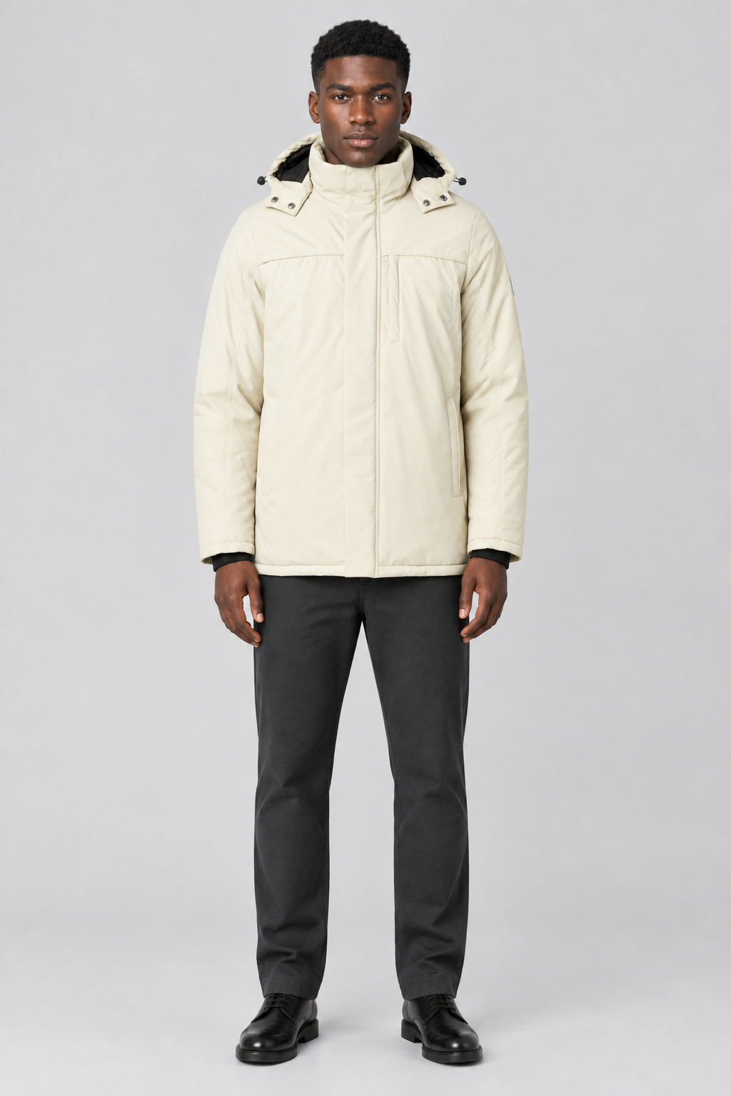 Mannelijk model met de lichtbeige Indicode Jas Viks met capuchon, volledig van voren gefotografeerd