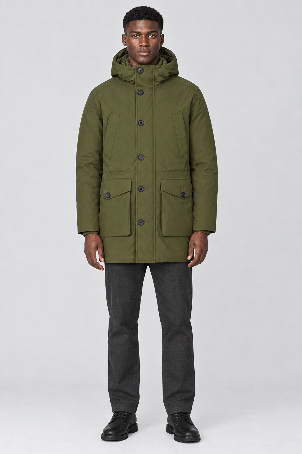 Mannelijk model met de olijfgroene Jack & Jones Parka City met capuchon en knoopsluiting, volledig van voren gefotografeerd