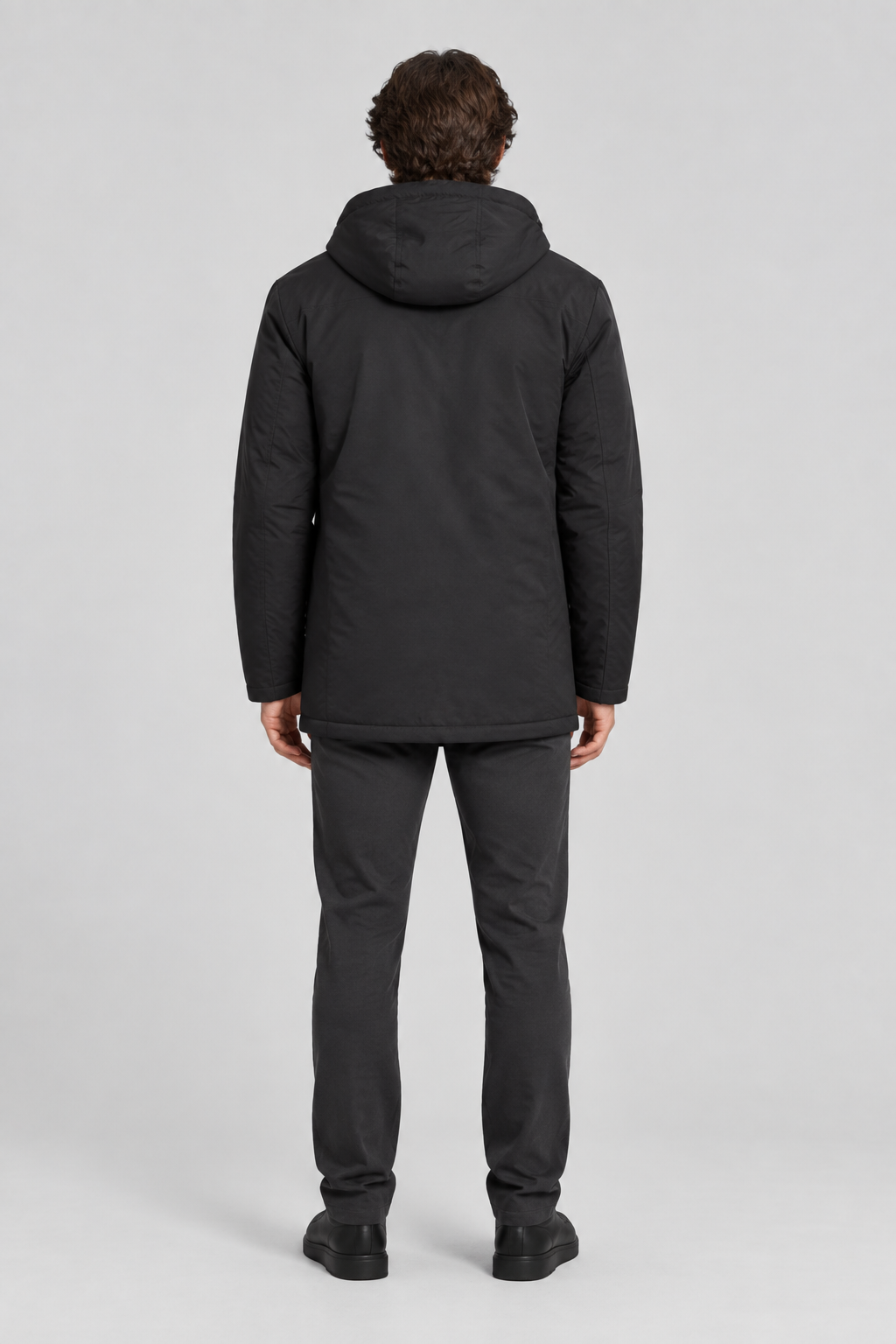 Mannelijk model met de zwarte Dan Fox Apparel Jas Jannik met capuchon, volledig van achteren gefotografeerd