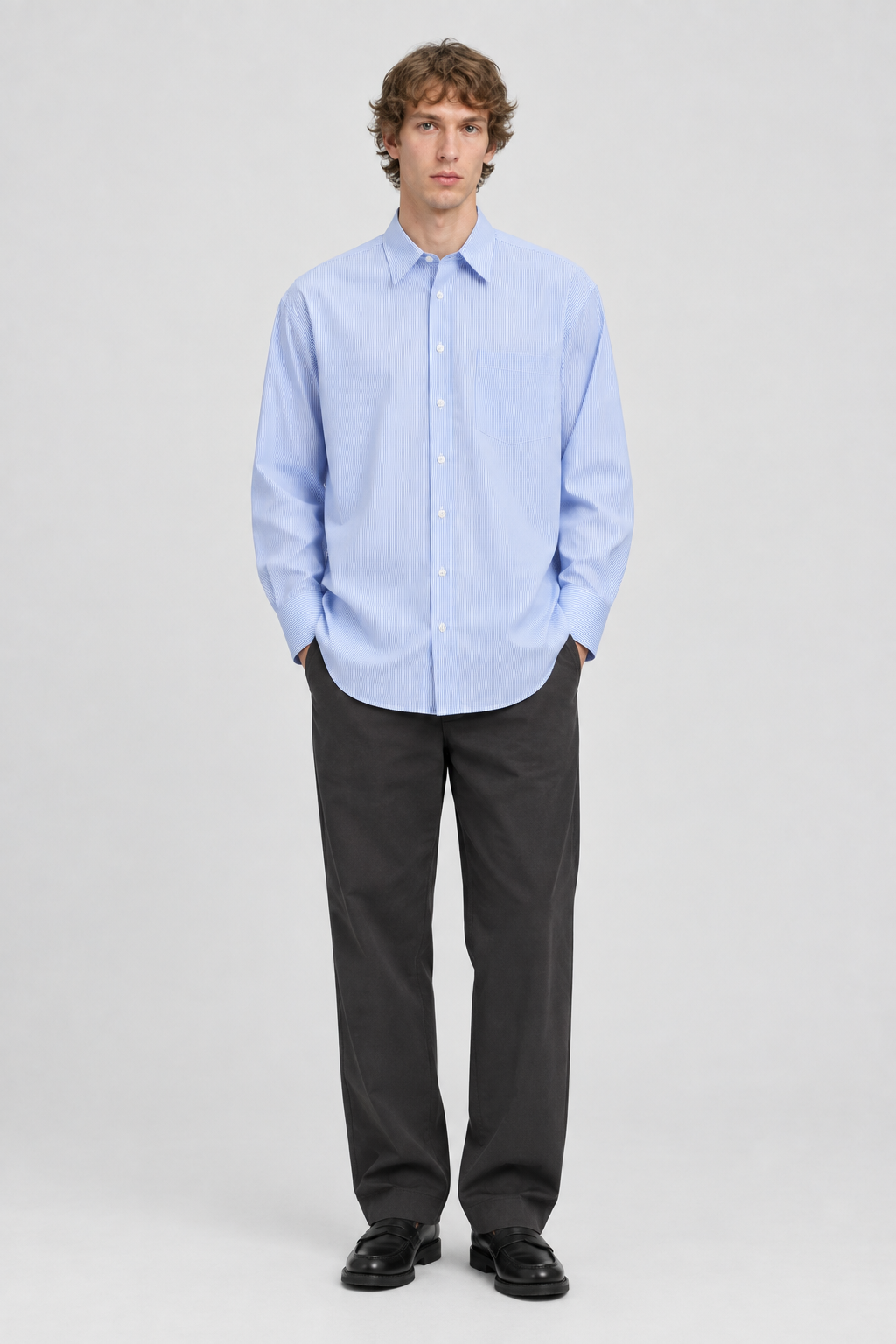 Mannelijk model met het lichtblauw-wit gestreepte Jack & Jones Oversized Overhemd Bill Poplin, volledig van voren gefotografeerd