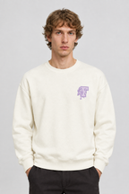 Vooraanzicht van een mannelijk model met de crèmekleurige Dan Fox Apparel Sweater Jesper met klein paars borstmotief